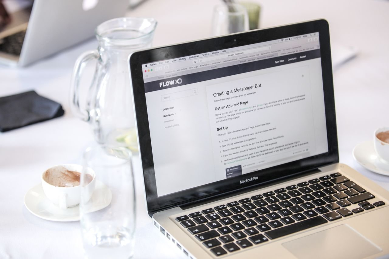 Mastering the First Impression: Your intriguing post title goes here Close-up of a MacBook Pro displaying a webpage, with coffee cups and water pitcher on a table.