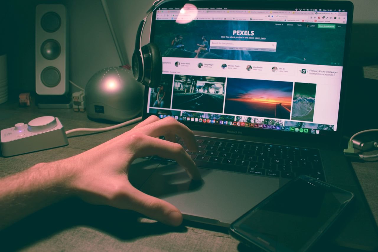 About Person browsing Pexels on a laptop with headphones and smartphone nearby.